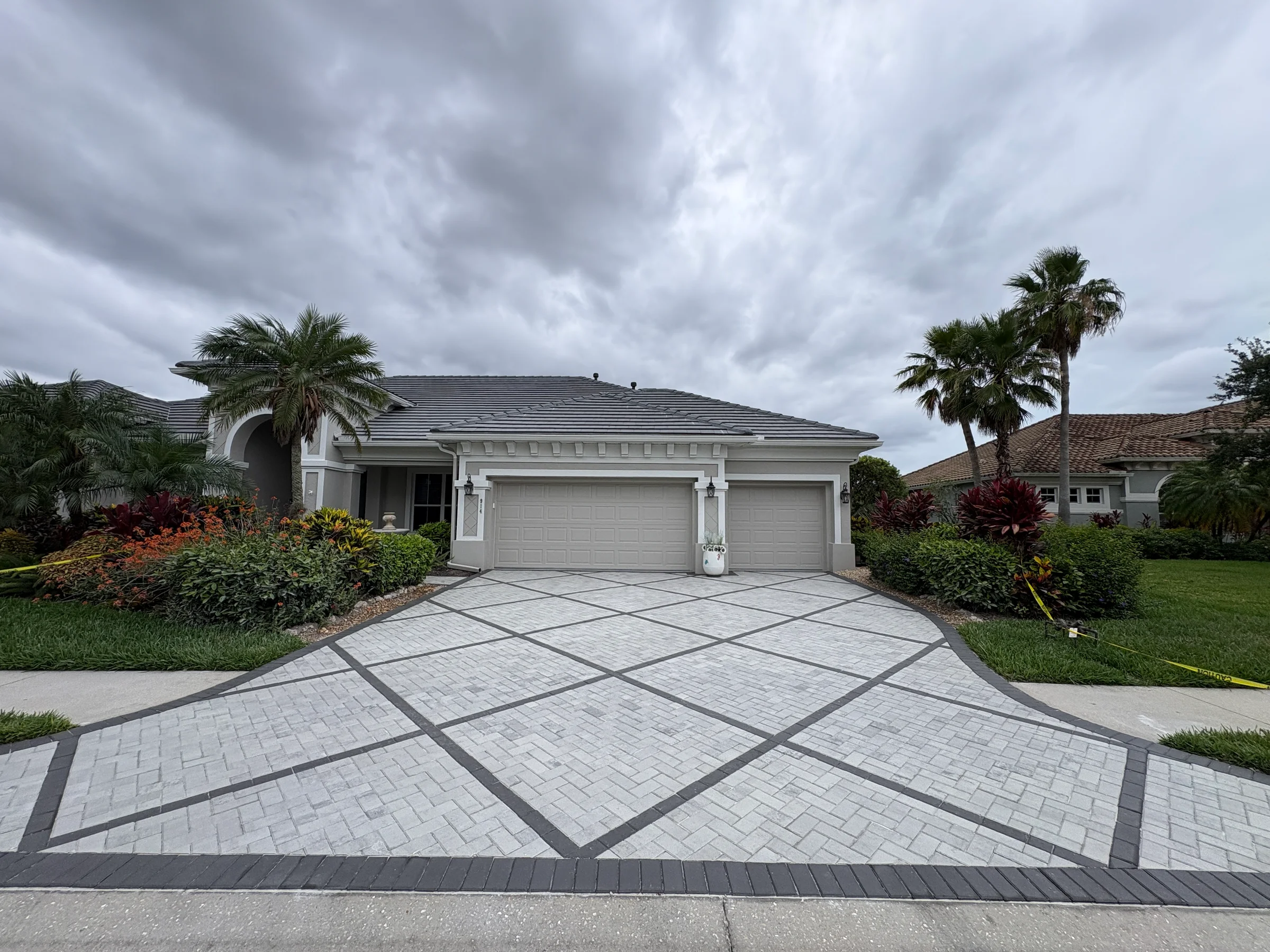 Finished pale paver driveway with a crisp charcoal geometric border
