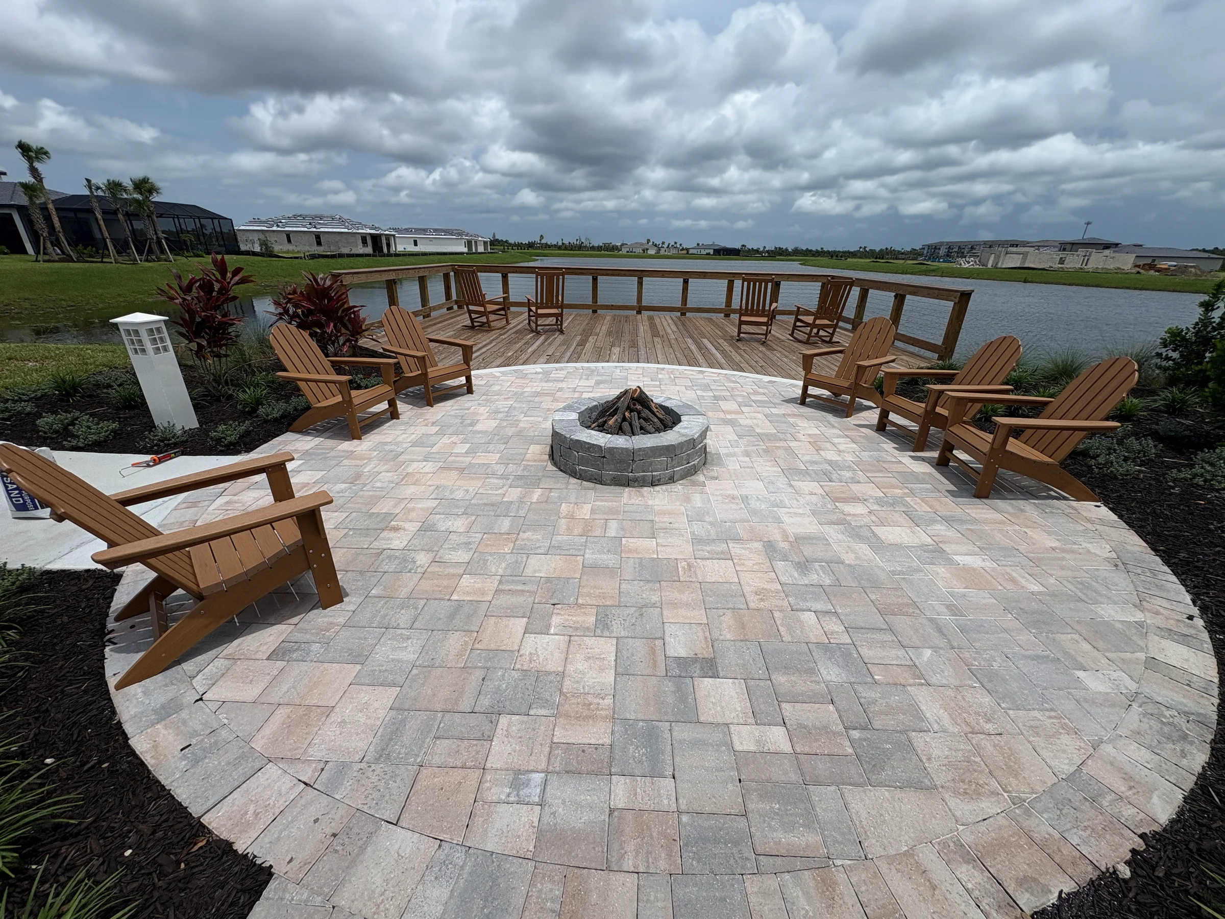 Round paver patio with a fire pit overlooking a pond