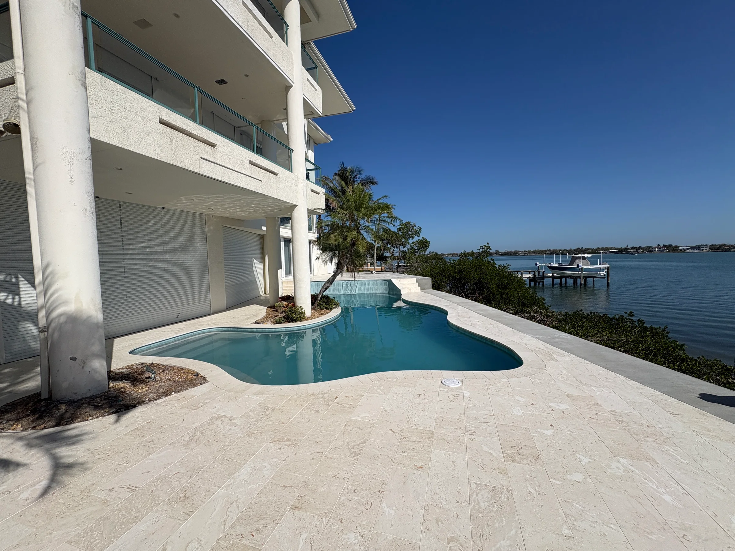 Finished light natural-stone pool deck at a waterfront Florida residence