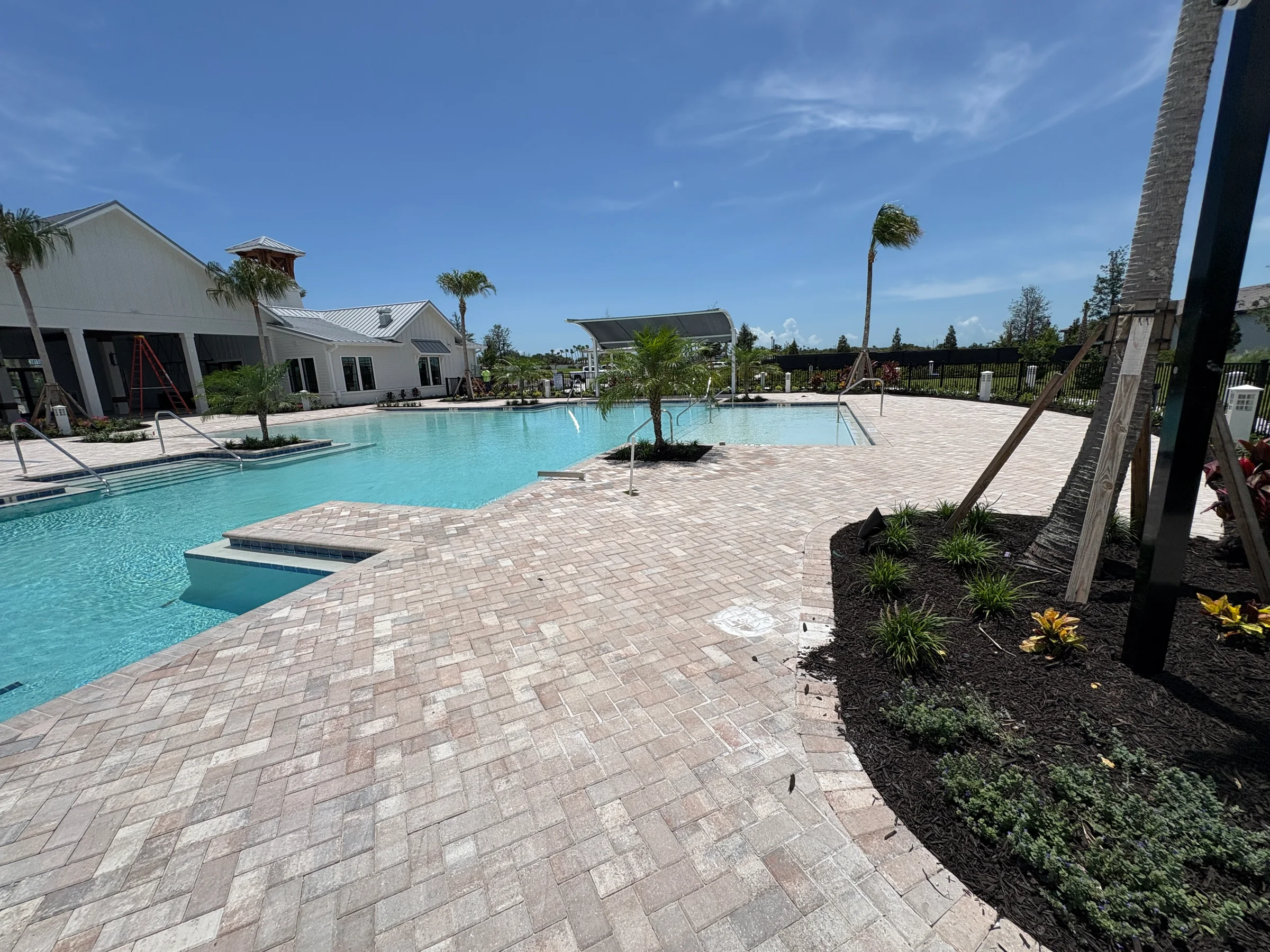 Large finished paver deck surrounding a community swimming pool